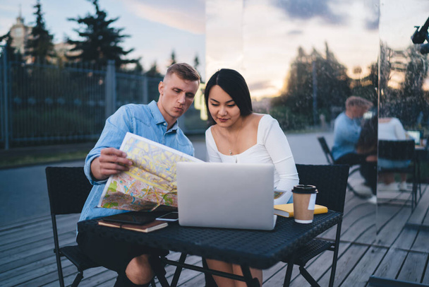 Young Caucasian couple in love planning together holidays using laptop computer and location map for choosing direction route and tracking GPS, male and female wanderers discussing travel tourism - Foto, Imagem
