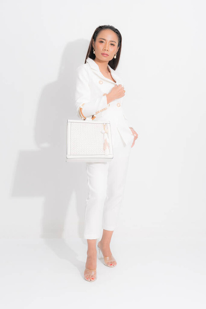 Fashion style catalog clothing for business woman black long hair natural make up wear white suit costume perfect body shape suit, carrying white bag at studio shoot on white background and shadow. - Fotografie, Obrázek