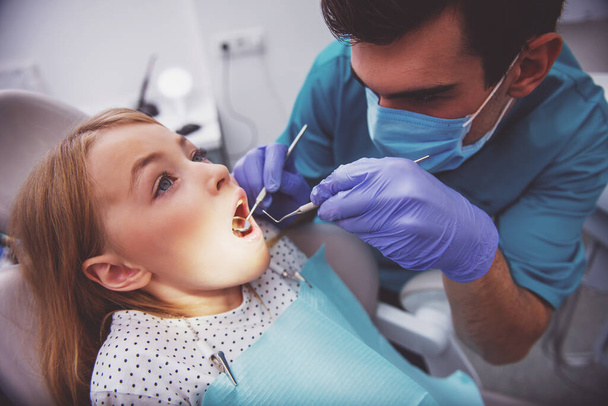 Dentist examine a little girl with an open mouth. Close-up - Фото, зображення