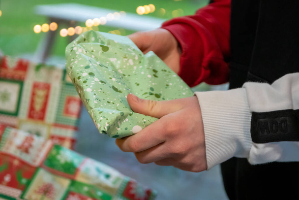 Европейский мальчик распаковывает и распаковывает рождественские подарки под елкой в канун Рождества с высоким напряжением, много приятного ожидания и полной радости и удовольствия для декоративных подарков в коробке - Фото, изображение