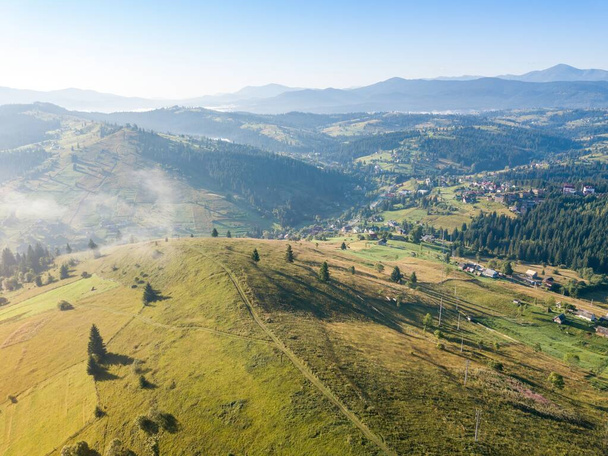 Köd a hegyekben kora reggel terjed végig a hegyek lejtőin. Ukrán Kárpátok reggel a ködben. Légi drónra néző. - Fotó, kép