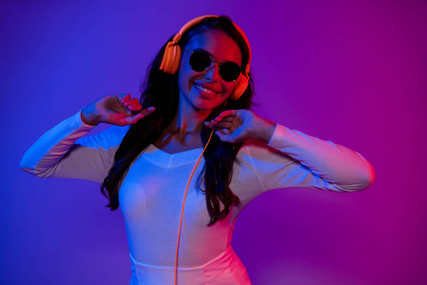 Photo of cool young brunette dancer lady listen music wearing earphones white dress eyewear isolated over neon color background - Foto, afbeelding