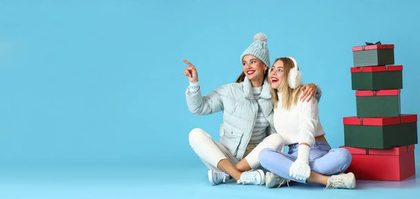 Young sisters with Christmas gifts on blue background with space for text - Fotó, kép