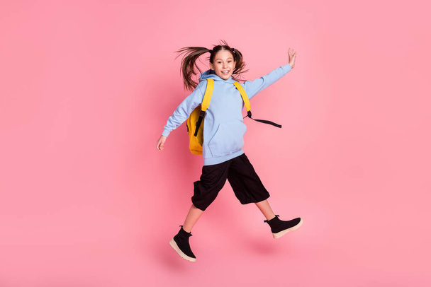 Full length body size photo of small schoolgirl with yellow rucksack jumping smiling isolated pastel pink color background - Фото, изображение