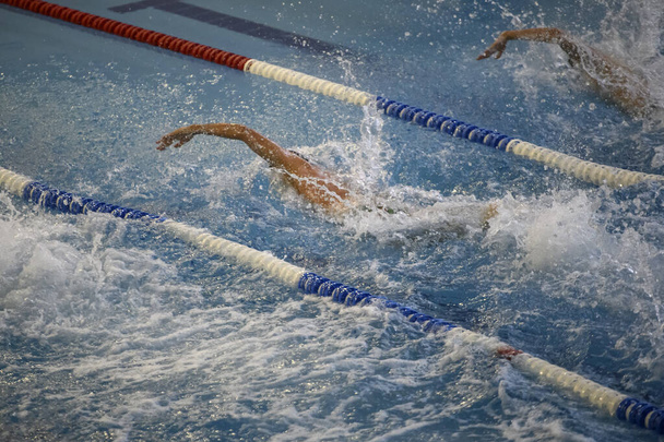 Профессиональная плавательная гонка в закрытом бассейне в спортивном центре. Высокое качество фото - Фото, изображение