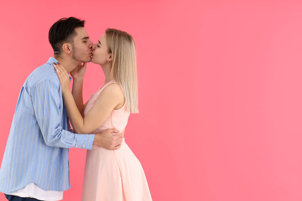 Cute and happy couple kissing on pink background - Фото, изображение