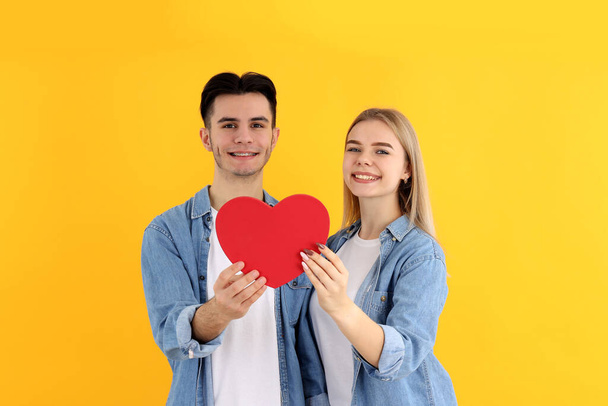 Χαριτωμένο ζευγάρι με καρδιά σε κίτρινο φόντο - Φωτογραφία, εικόνα