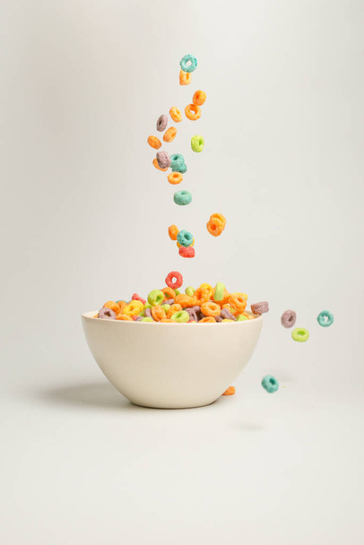 Colorful cereal box for morning breakfast. Corn flakes falling to the white bowl. Motion. Copyspace. - Fotografie, Obrázek
