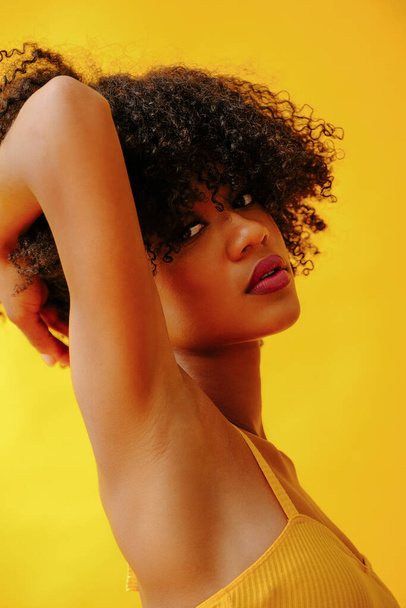 portré gyönyörű fiatal afro-amerikai nő fényes nyári ruha pózol elszigetelt sárga háttér - Fotó, kép