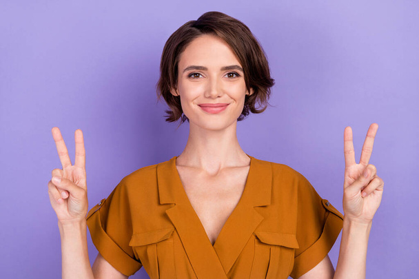 Photo of young attractive woman happy positive smile show peace cool v-sign isolated over violet color background - Foto, Imagem