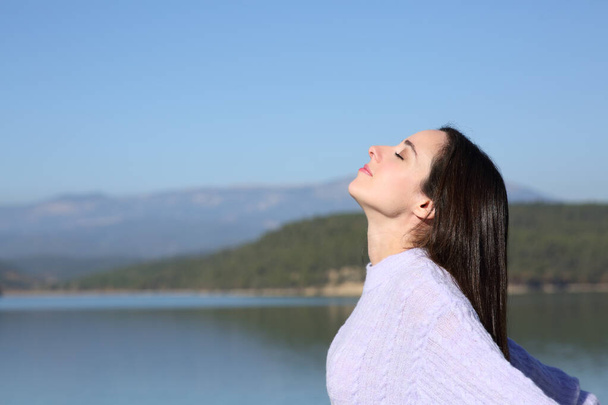 Side view portrait of a relaxed woman breathing fresh air in a mountain lake - Photo, Image