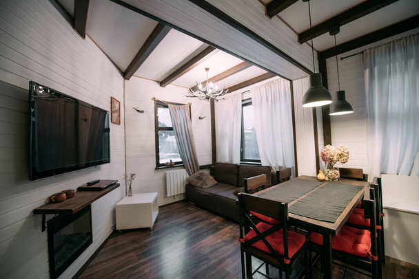 Cocina combinada y sala de estar en una casa de campo escandinava de madera. Acogedor primer piso de una pequeña casa de madera moderna. - Foto, Imagen