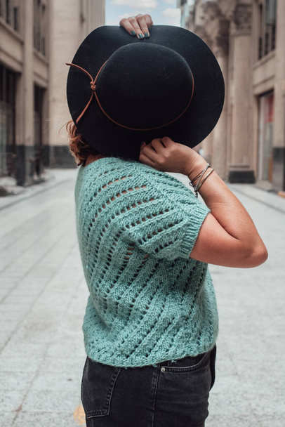 Imagem de uma mulher escondendo seu rosto com um chapéu preto no meio de uma rua solitária - Foto, Imagem