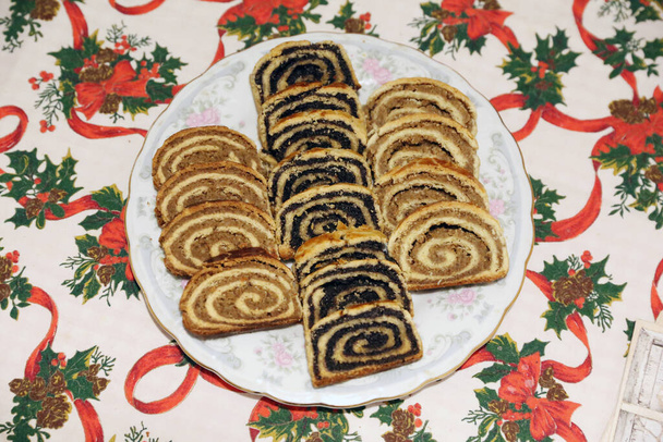 Homemade poppy seeds or walnut roll cakes aka beigli or bejgli slices like a winged angel on plate. Traditional hungarian christmas sliced rolled cakes on table - 写真・画像