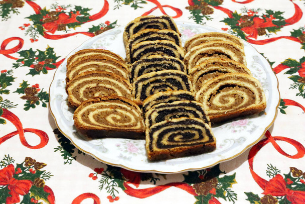Homemade poppy seeds or walnut roll cakes aka beigli or bejgli slices like a winged angel on plate. Traditional hungarian christmas sliced rolled cakes on table - Fotó, kép