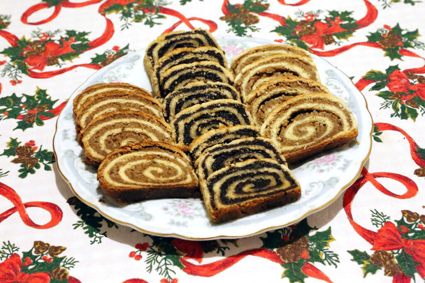 Homemade poppy seeds or walnut roll cakes aka beigli or bejgli slices like a winged angel on plate. Traditional hungarian christmas sliced rolled cakes on table - Zdjęcie, obraz