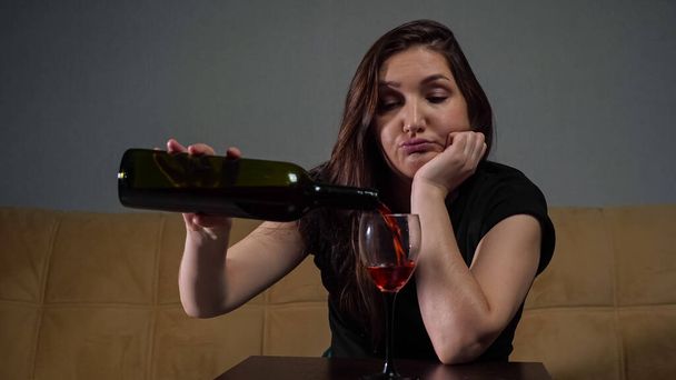 Frau gießt Wein in Glas und sitzt gestresst und deprimiert - Foto, Bild