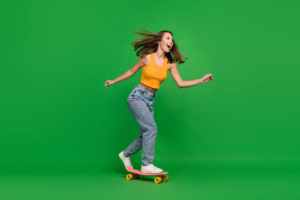Full length photo of young impressed brunette lady go wear top jeans shoes isolated on green background - Fotografie, Obrázek