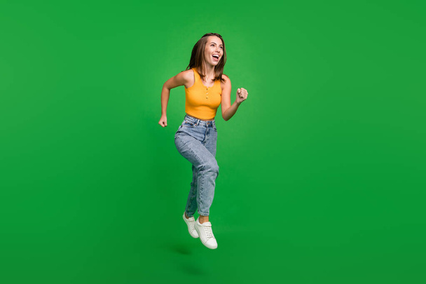 Full body photo of millennial funky brunette lady jump wear top jeans shoes isolated on green background - Foto, Imagen