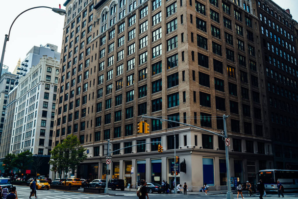 High stone tower with large windows on crossroad with driving taxis and public transport in downtown of New York City - Fotó, kép