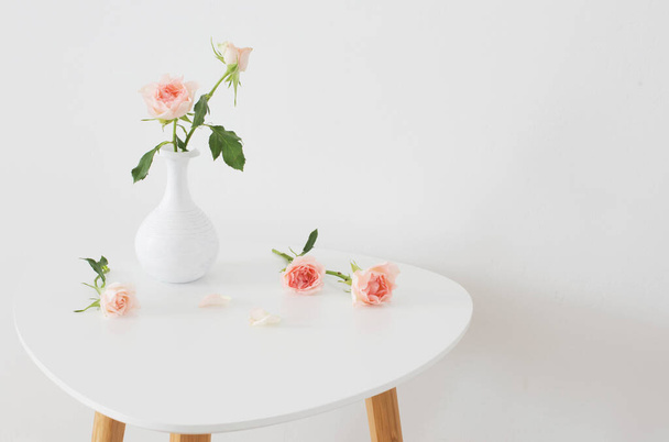 pink roses in white vase on  table on background white wall - Foto, Imagen