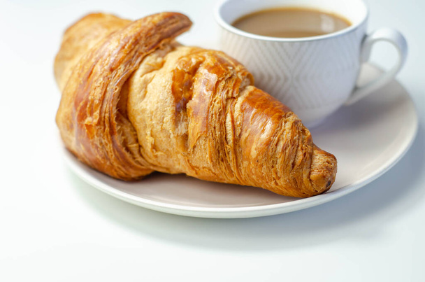 Croissant met chocolade op een bord met koffie in een kopje - Foto, afbeelding