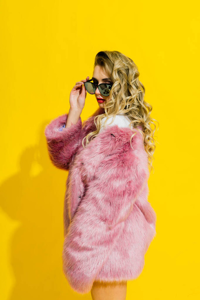 Gorgeous young woman posing in a luxurious fur coat and bodysuit. Fashion, beauty. Studio shot. - Фото, изображение