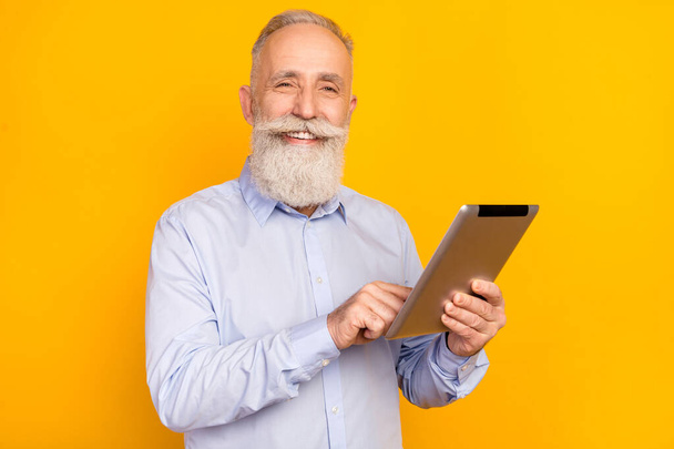 Photo of pretty charming mature man dressed formal outfit smiling typing modern device isolated yellow color background - Φωτογραφία, εικόνα