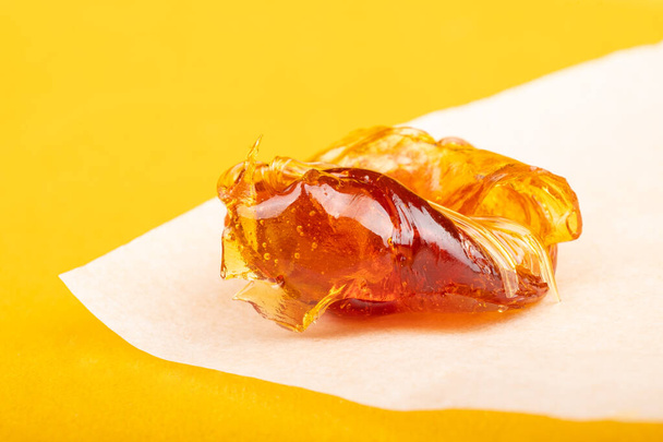 piece of resin cannabis concentrate on yellow background medical marijuana extract - Foto, Imagem