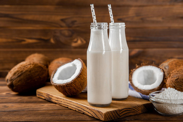 Coconut yogurt and coconuts on a wooden background. Close-up. - Foto, afbeelding