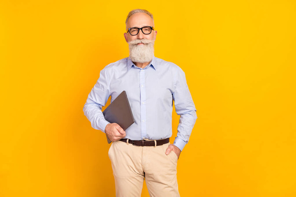 Photo of cheerful happy old man hold laptop good mood pocket isolated on shine yellow color background - Zdjęcie, obraz