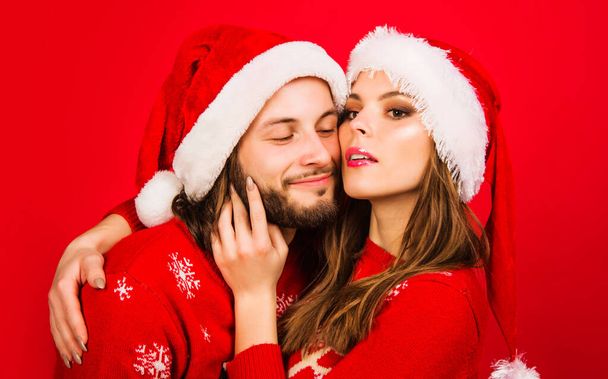サンタの帽子のクリスマスカップルが抱きつく。ロマンチックな関係だ。お正月のお祝い。閉鎖. - 写真・画像