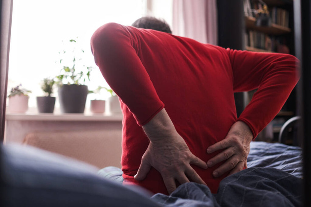 Ανώτερος άνθρωπος που υποφέρει από πόνο στην πλάτη ή χαλινάρια στο σπίτι - Φωτογραφία, εικόνα