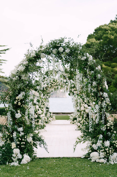 White walkway through a row of wedding arches on a green lawn - Foto, Bild