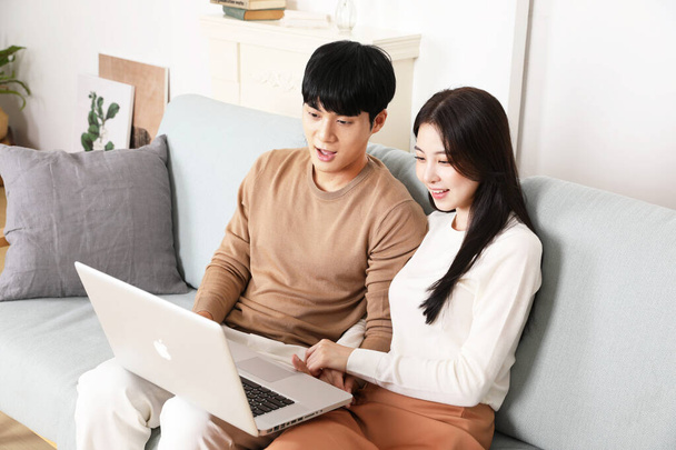Asian Korean couple having cozy time with laptop streaming video or movie, winter home date concept - Photo, Image