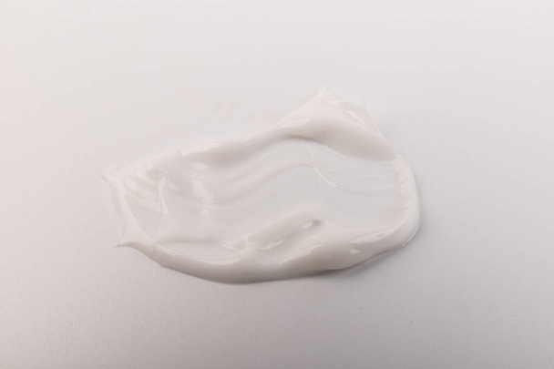 White smear of cosmetic cream isolated on light background. Creamy foundation texture. Smear of face cream. Texture of cream background - Photo, Image