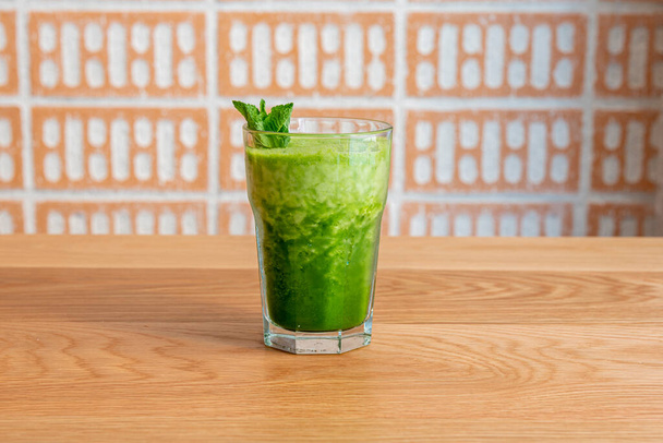 Detox smoothie with spinach and kiwi and topped with some mint leaves on wooden table - Foto, Imagem