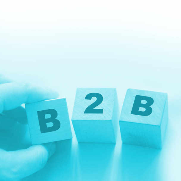 B2B abbreviation in letters on wooden cubes. Business to Busness concept Hand put a cube B to the row. Business marketing strategy concept. - Foto, Imagem
