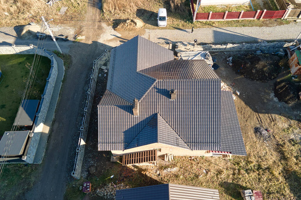Aerial view of house roof top covered with ceramic shingles. Tiled covering of building under construction - Photo, Image