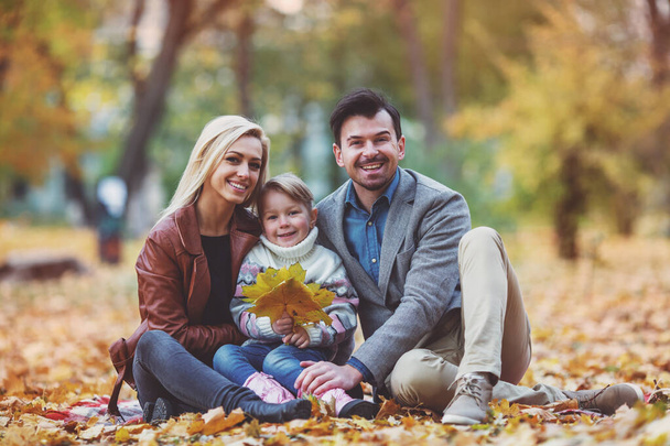 Young happy family while walking in the autumn park. - Photo, Image