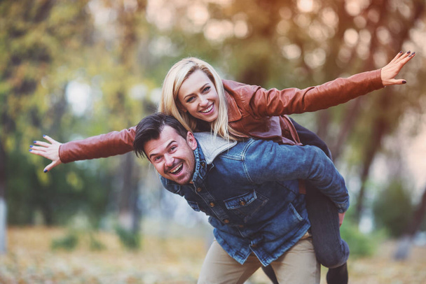 Happy young couple while walking in the autumn park. - Photo, Image
