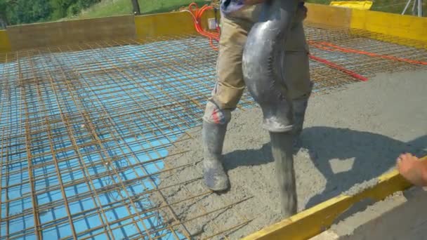 CLOSE UP: Team of builders pours a concrete slab over the reinforced metal mesh. - Filmati, video