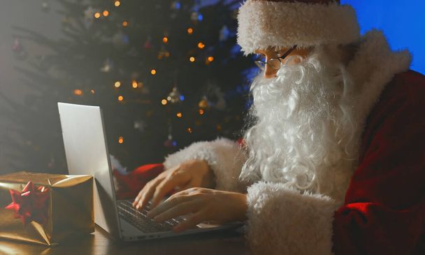Санта Клаус печатает письмо на компьютере.. - Фото, изображение