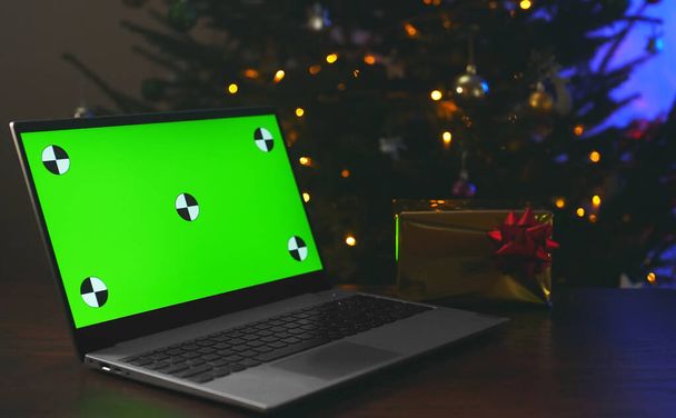 Laptop karácsonyfával és ajándékkal. Zöld chroma kulcs a hirdetéshez. - Fotó, kép