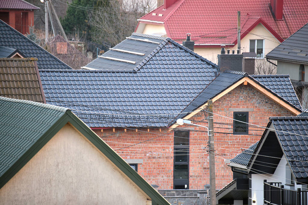 農村部郊外の金属とセラミックの帯状疱疹で覆われた屋根の上の住宅 - 写真・画像