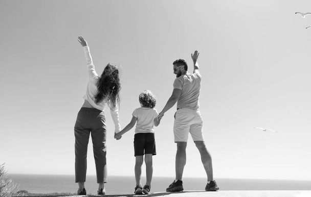 família de mãe pai e filho menino olhando no futuro de mãos dadas no verão, visão traseira, adoção - Foto, Imagem