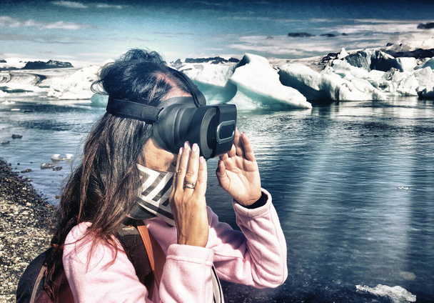 Γυναίκα με γυαλιά εικονικής πραγματικότητας που επισκέπτεται τη λιμνοθάλασσα Jokulsarlon. - Φωτογραφία, εικόνα
