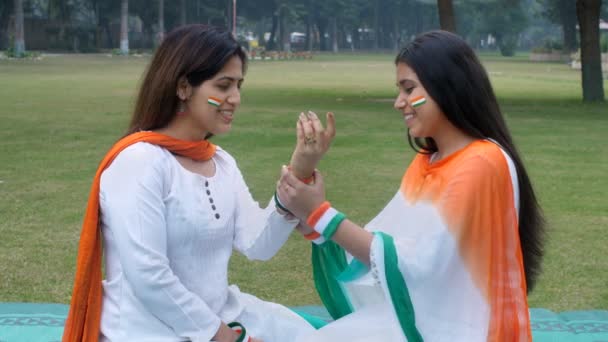 "Cumhuriyet Günü 'nde üç renkli bilezik takan çekici bir kadın. Hindistan renginde giyinmiş iki kadın parkta oturuyor Bağımsızlık Günü, vatansever ruh hali, geleneksel elbise" - Video, Çekim