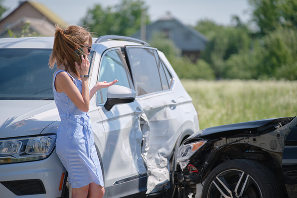 路上で電話で話す悲しい女性ドライバーは、交通事故後の緊急サービスを求めています。道路の安全と保険の概念 - 写真・画像