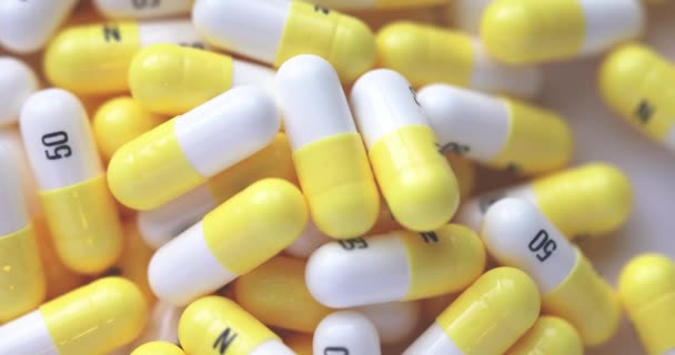 A Macro close-up of a rotating table with white and yellow N 50 capsules. - Filmagem, Vídeo